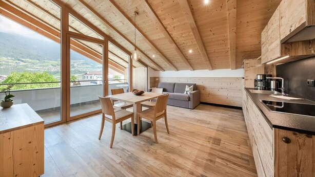Une cuisine moderne avec des poutres en bois, un coin repas avec une table et des chaises, et un canapé.