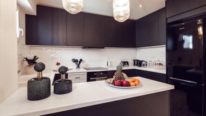 Una cucina moderna con mobili scuri, un piano di lavoro bianco e un frigorifero nero.