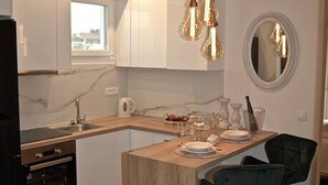 Una cucina moderna con isola centrale, illuminazione a sospensione e zona pranzo con uno specchio e sgabelli da bar.