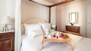 Un letto rifatto con cura, un vassoio con prodotti per la colazione, una lampada da comodino e una cassettiera in legno.