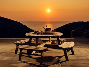 Enjoy a meal on the outdoor terrace with a view of the water and distant hills.