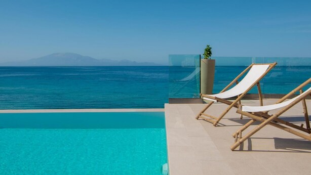 A clear view of a swimming pool with a wooden deck and two lounge chairs facing the sea. - Villa Bala - Seaside Luxury Villa - Villa Bala - Seaside Luxury Villa (Zakynthos)