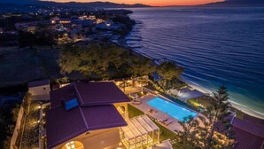 A coastal property with a swimming pool, a covered patio, and a view of the sea at sunset. - Villa Bala - Seaside Luxury Villa - Villa Bala - Seaside Luxury Villa (Zakynthos)