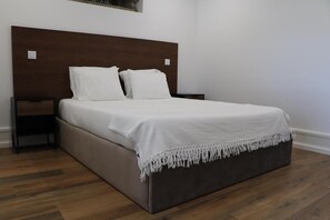 Ein Standard-Hotelzimmer mit einem hölzernen Kopfteil, einem Bett mit weißen Bettwäsche, einem Nachttisch und einem Holzboden.