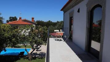 Una casa con piscina, un patio con mesa y sillas, y vistas del entorno.