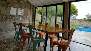 Ein Essbereich mit einer Steinwand, einem Holztisch und bunten Stühlen.