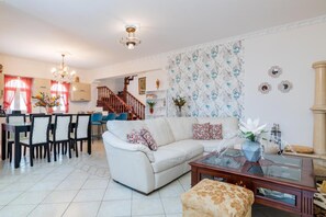 A spacious living room with a sofa, coffee table, and dining area with chairs.