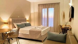 A bedroom with a bed, a sofa, a dining table, and chairs. - Apartment Hotel 'Sunset Supreme Studio A' near Beach with Pool, Garden & Wi-Fi (Lefkada)