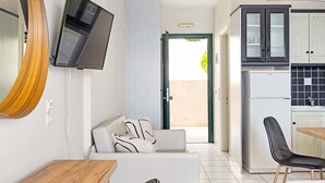 A modern kitchen with a refrigerator, cabinets, and a dining area with a table and chairs. - Apartment Hotel 'Sunset Supreme Studio A' near Beach with Pool, Garden & Wi-Fi (Lefkada)