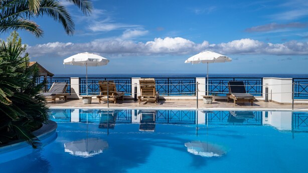 A pool with clear blue water, lounge chairs, and umbrellas, with a view of the ocean. - Apartment Hotel 'Sunset Supreme Studio A' near Beach with Pool, Garden & Wi-Fi (Lefkada)