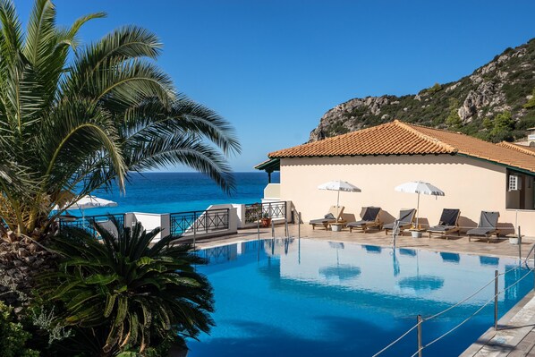 Une piscine dotée de chaises longues et de parasols, avec vue sur la mer.