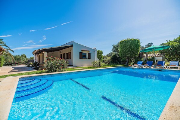 A clear blue swimming pool with lounge chairs and a small building with a balcony. - Holiday Home Villa Moreno II with Pool, Garden, and Wi-Fi (Pollensa)