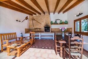 A rustic kitchen with wooden beams, a brick wall, and a dining area with wooden furniture. -  Holiday home Villa Moreno II with Pool, Garden & Wi-Fi (Pollensa)