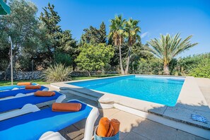 A swimming pool with lounge chairs and towels, surrounded by trees and a stone wall. - Holiday Home Villa Moreno II with Pool, Garden, and Wi-Fi (Pollensa)
