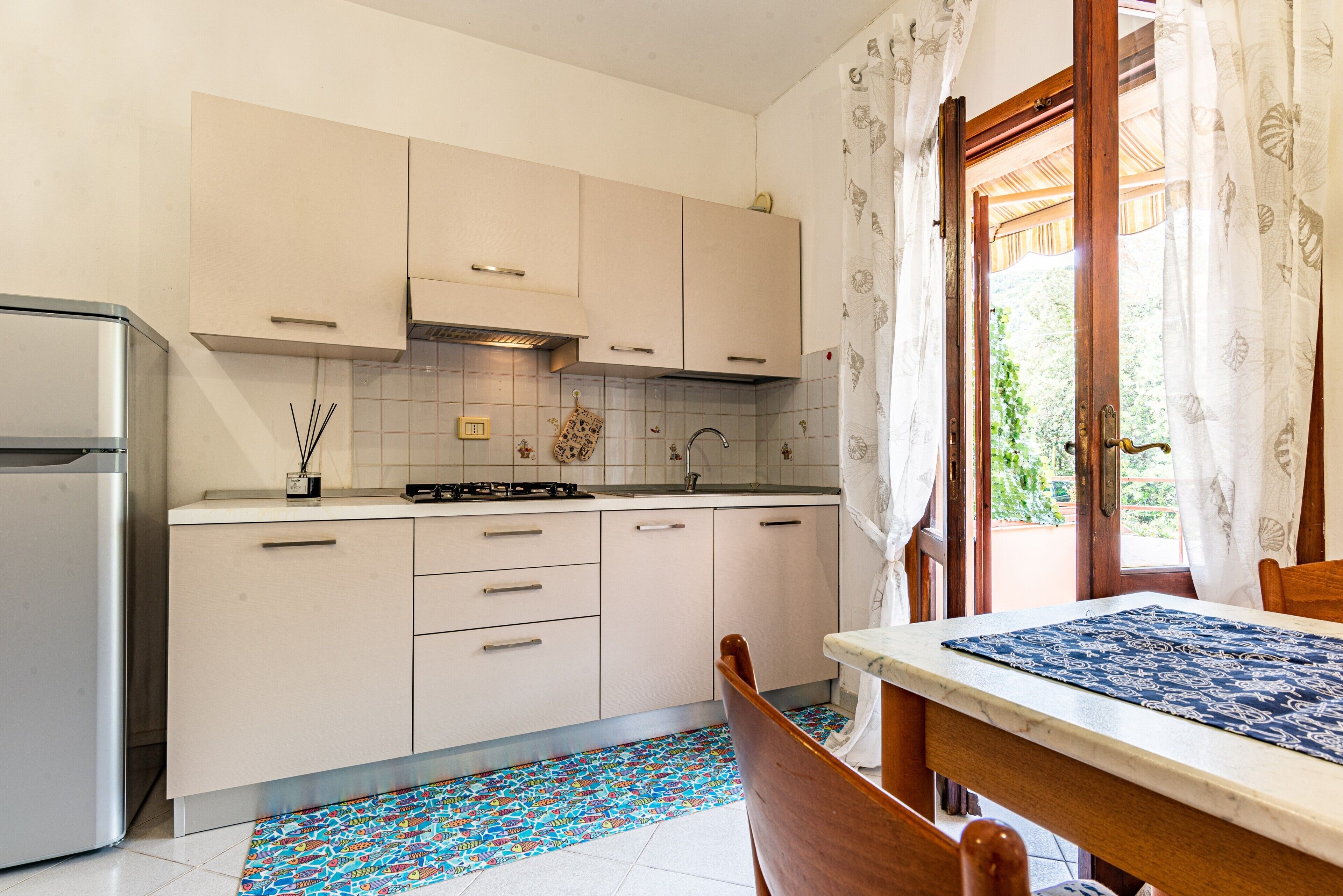 A kitchen with white cabinets, a stainless steel refrigerator, a tiled backsplash, and a patterned floor.