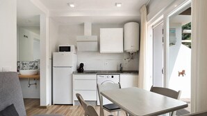 Uma cozinha compacta com máquina de lavar louça, micro-ondas e armário branco.