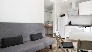 Uma cozinha moderna com armários brancos, forno embutido e micro-ondas.