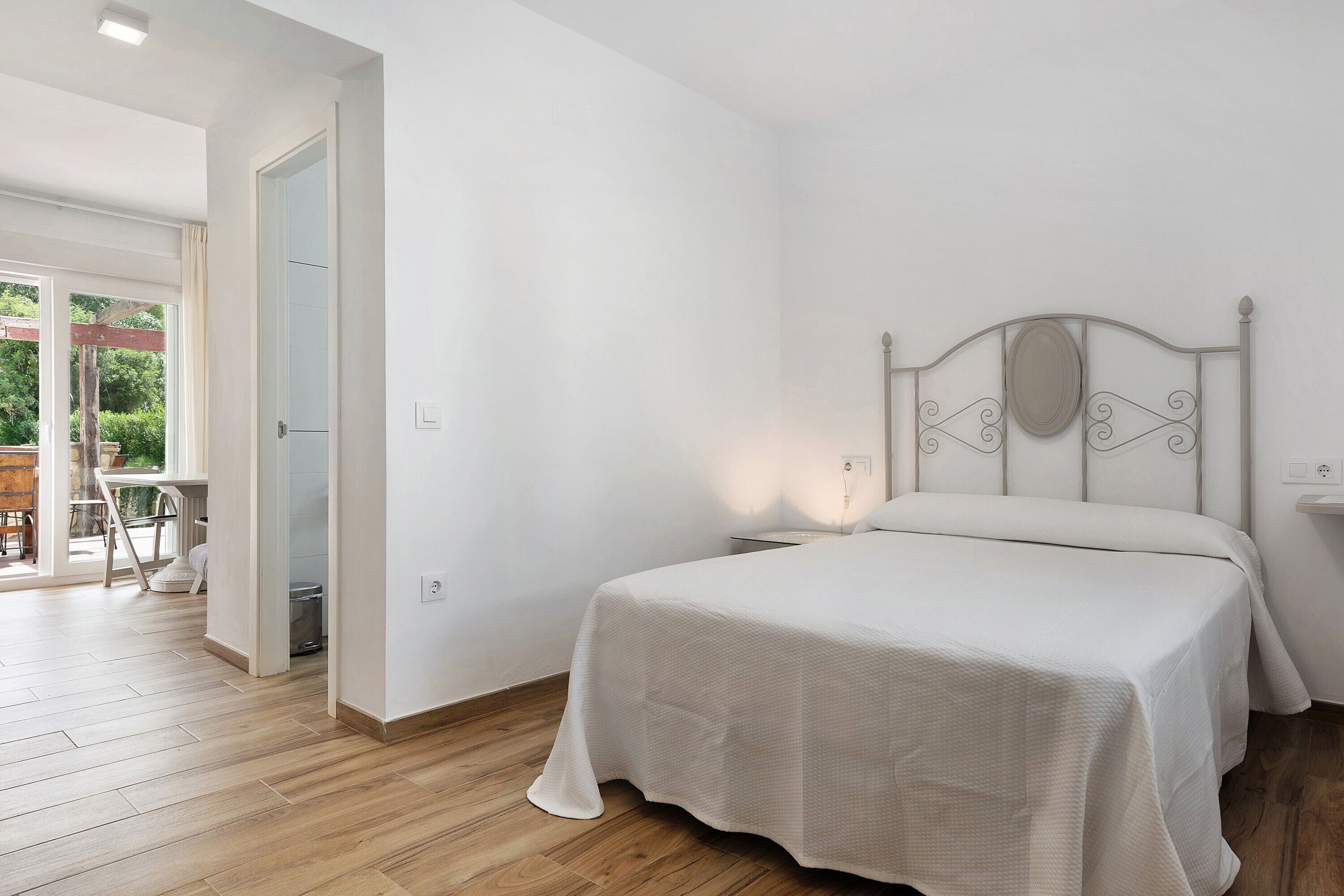 Une chambre à coucher comprenant un lit, une table de chevet, une fenêtre et une porte donnant sur un balcon.