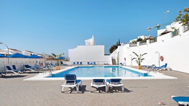 A swimming pool with lounge chairs, a white building, and a clear blue sky. - Holiday Home 'Casa Begines' close to City Centre with Shared Pool (Vejer)