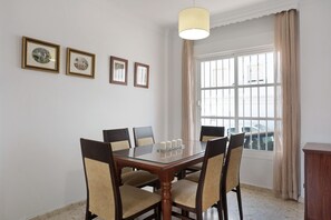 Une salle à manger avec une table à plateau en verre, six chaises et trois tableaux encadrés accrochés au mur.