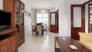 A room with a wooden cabinet, a television, a dining table with chairs, and a sofa. - Holiday Home 'Casa Begines' close to City Centre with Shared Pool (Vejer)