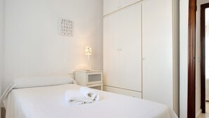 A neatly made bed with a folded towel, a bedside lamp, and a wardrobe in a clean, white room. - Holiday Home 'Casa Begines' close to City Centre with Shared Pool (Vejer)