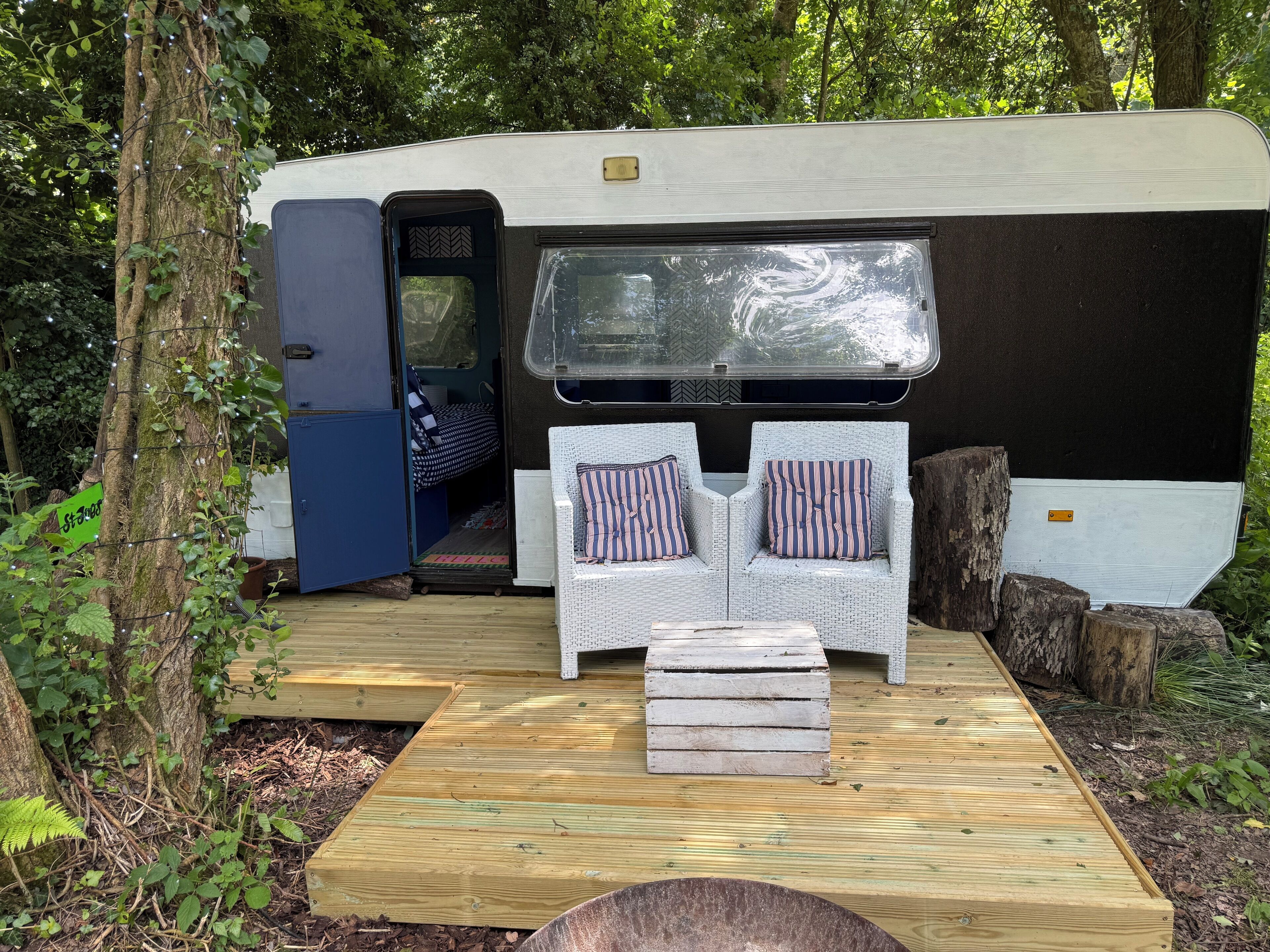 A mobile home with a porch area featuring wicker furniture and a bench.