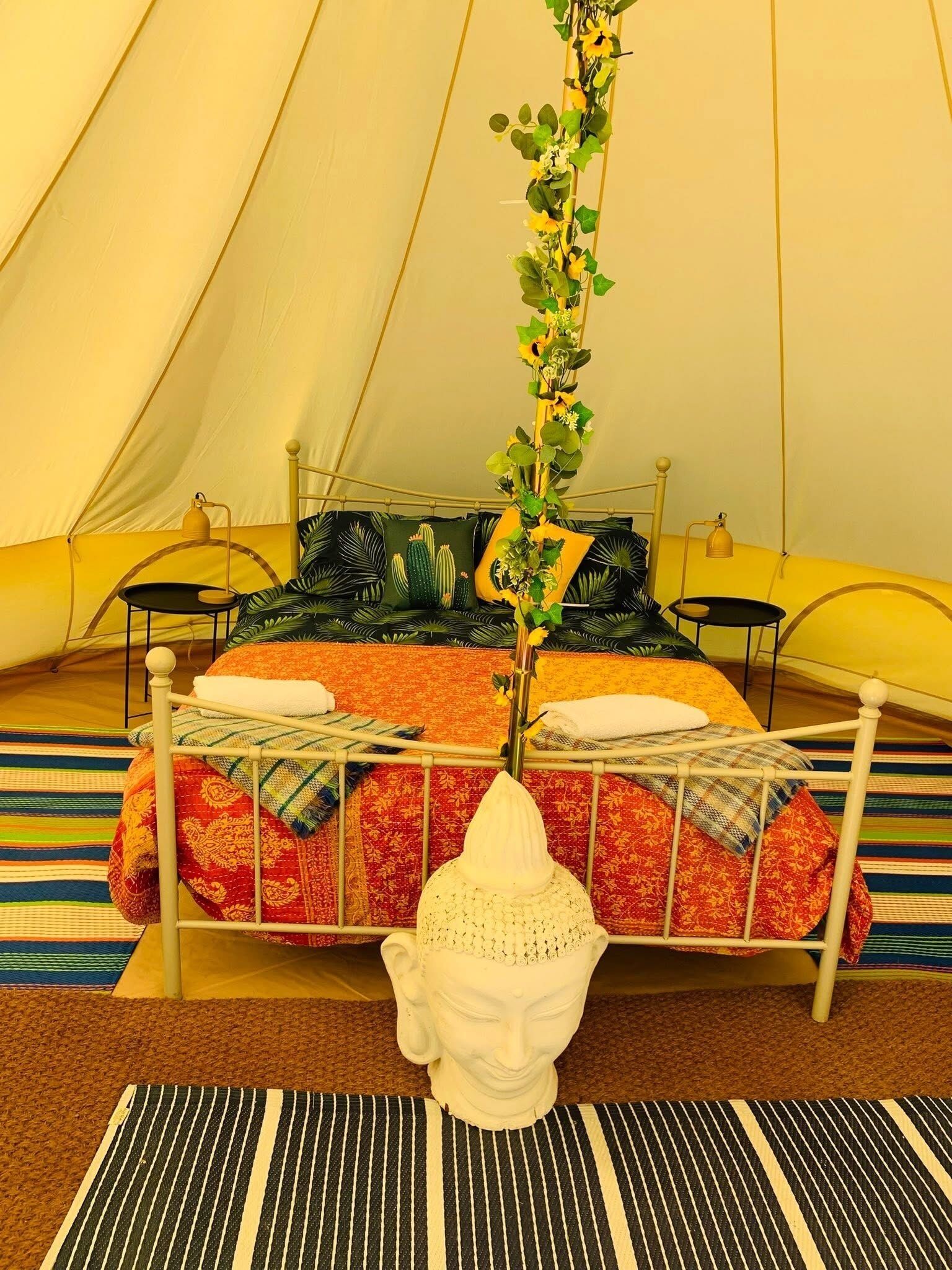 Una carpa con una cama, almohadas, una lámpara y una planta decorativa.