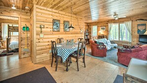 A log cabin interior with a dining area, a sofa, and a television.