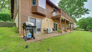 Una baita di legno con veranda coperta, barbecue e mobili da patio.