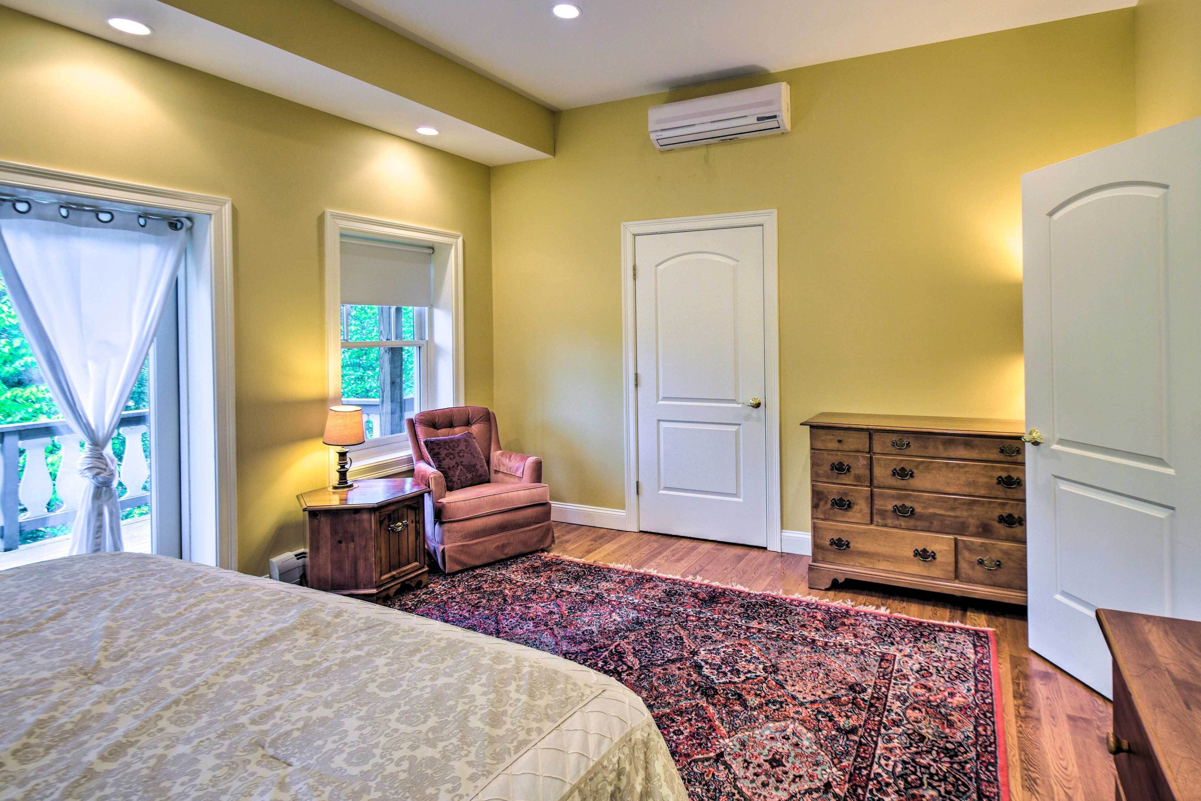 A bedroom with a bed, a chair, a dresser, and a door.