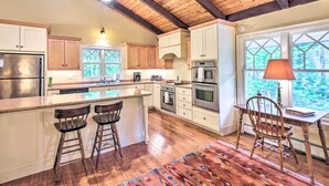 A kitchen with wooden beams, a large island with stools, stainless steel appliances, and a view through a window. - 4 Mi to Ski Slopes: Family-Friendly Bartlett Home! (Bartlett)