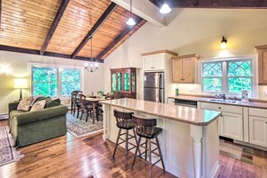 Una cocina amplia con techo de madera, una isla central con taburetes y un refrigerador.