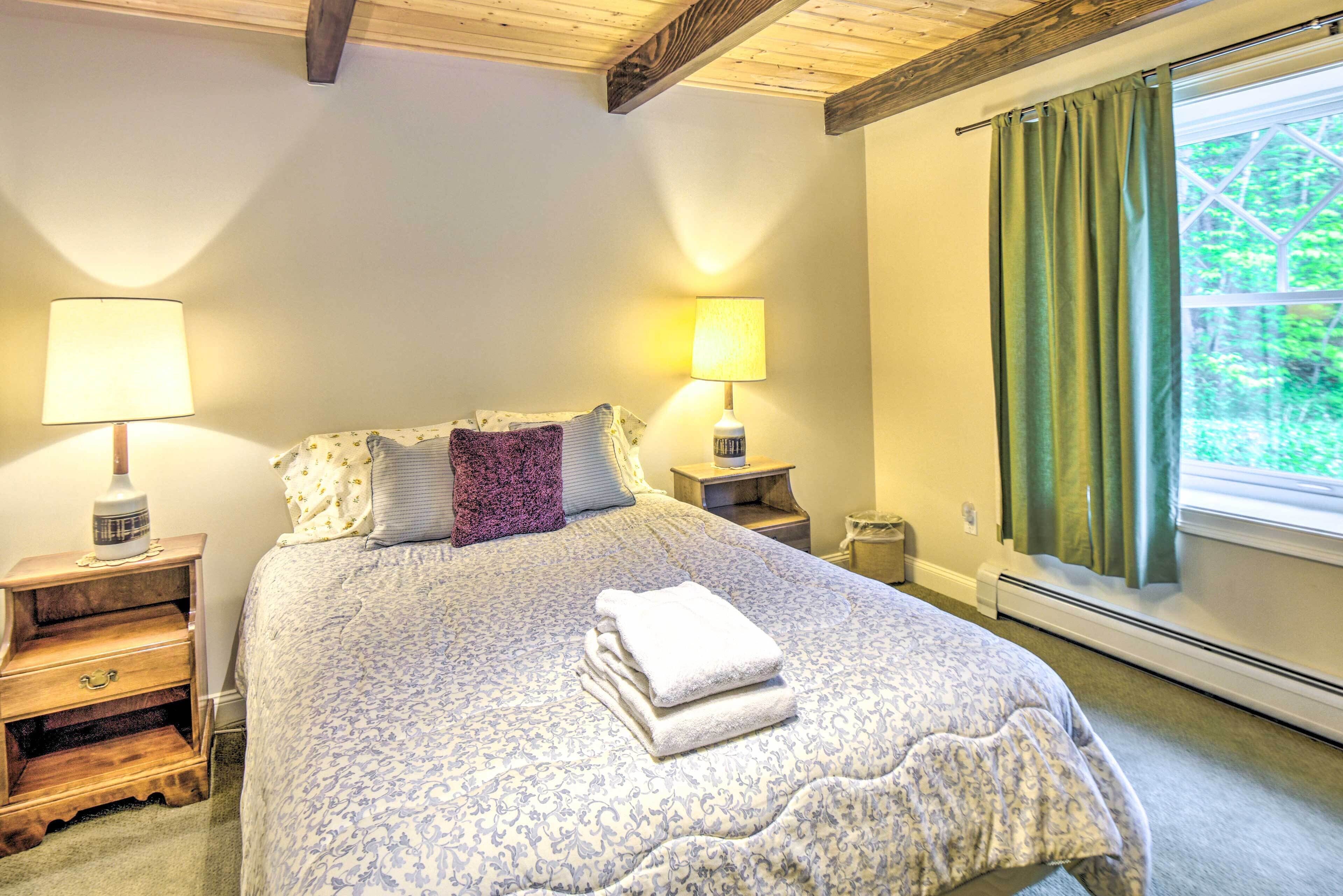 A neatly made bed with a patterned bedspread and two bedside lamps.