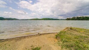 Une vue sur le lac, avec une plage de galets et des zones herbeuses.