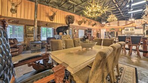 Un interior rústico con una gran mesa de madera, sillas de cuero y diversas cabezas de animales montadas en las paredes.