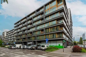 En byggnad med flera våningar och en modern arkitektonisk design, med balkonger och stora fönster.