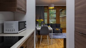 Una cocina compacta con microondas, una zona de comedor con mesa y sillas, un sofá y una lámpara colgante.