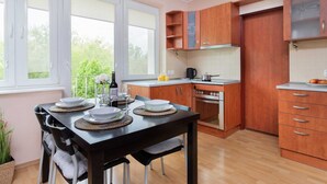 Una cocina moderna con armarios de madera, una mesa de comedor con platos y vasos, y una ventana con vistas a zonas verdes.