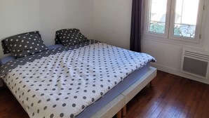 A bedroom with a bed, a round mirror, and a window with curtains.