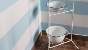Une étagère en métal blanc à trois niveaux, chaque niveau étant surmonté d’un bol blanc.
