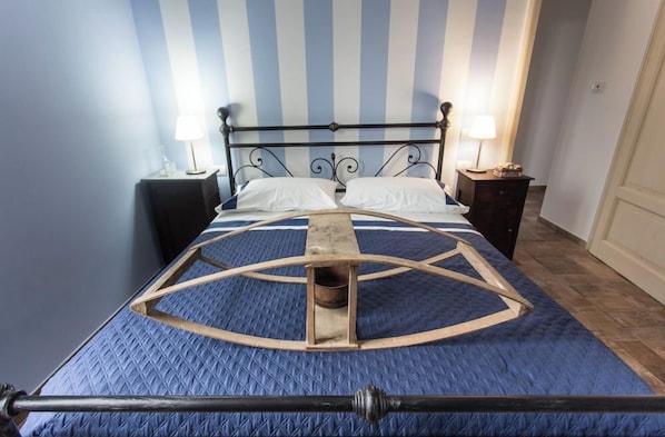 Un lit avec un cadre en métal, deux tables de chevet avec des lampes et un mur à rayures.
