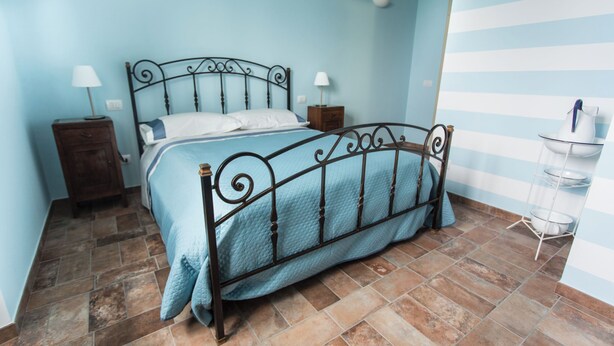 Un lit bien fait, avec un cadre en métal, deux tables de chevet avec des lampes et un mur à rayures.