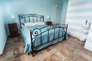 Un lit bien fait, avec un cadre en métal, deux tables de chevet avec des lampes et un mur à rayures.