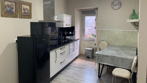 Uma cozinha compacta com geladeira preta, armários brancos e uma janela com vista.