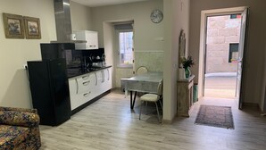 Cozinha compacta com área de refeições, sofá e vista para a rua.