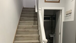 Uma escadaria com degraus de madeira e balaústres brancos.