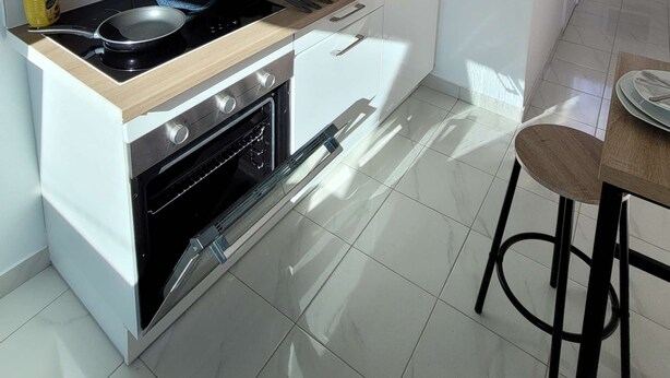 Una cocina moderna con armarios blancos, microondas, estufa y lavabo.