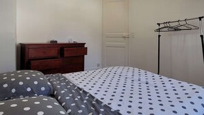Un dormitorio con cama, cómoda, puerta y lámpara en el techo.
