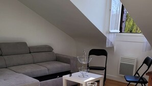 Un comedor con una mesa preparada para dos, un sofá gris, una mesita blanca y una silla.